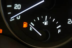 Low fuel light on car dash board with fuel dial on empty