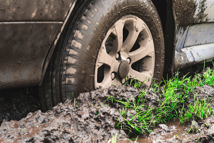 Car with wheel stuck in mud requiring a winch out